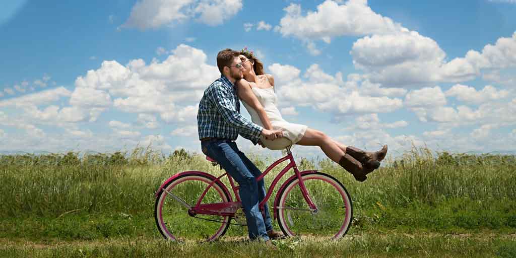 Couple riding bike through a field