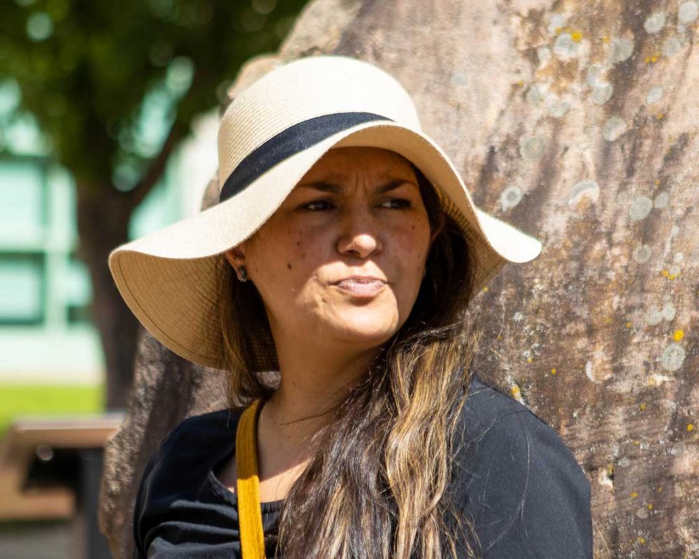 A metis woman wearing a flopy hat looking away from the camera