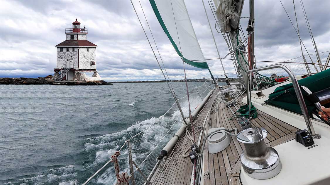 A sailboat sailing towards a lighthhouse on Lake Superior