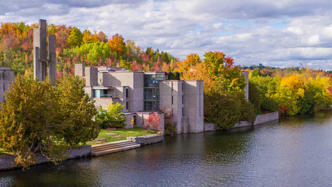 modern buildings surrounded by colourful trees beside the Otonabee River in Peterborough, Ontario