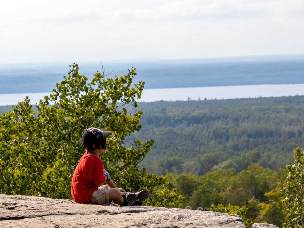 A boy sits atop the Cup and Saucer Trail in M'Chigeeng Ontario