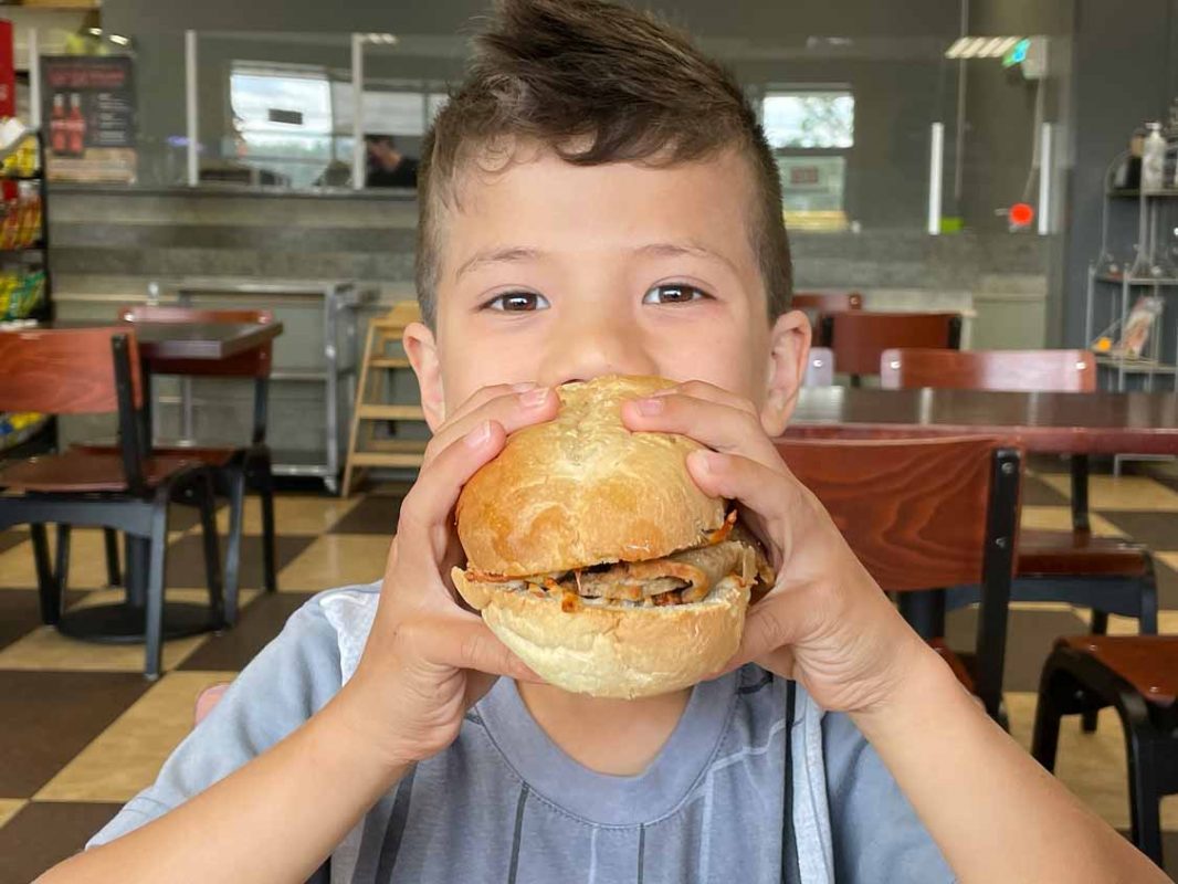 A boy eating a large sandwich from Cara's Deli in Sudbury, Ontario