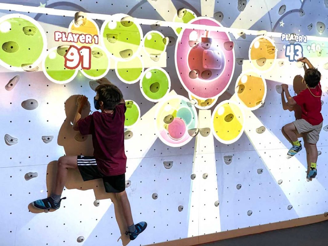 Two kids practice bouldering on an artificial reality bouldering wall