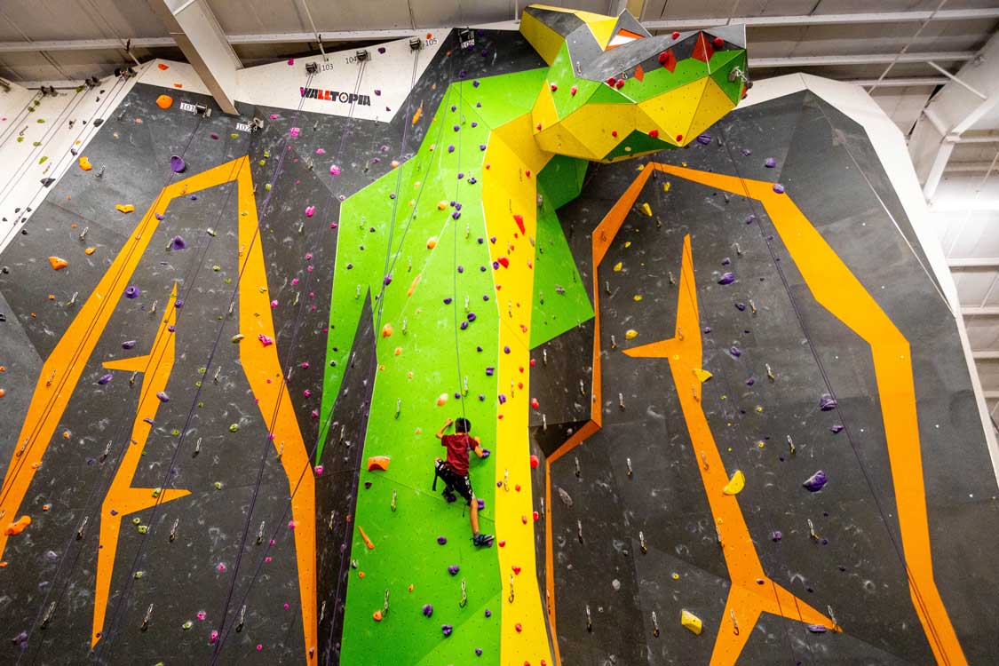 A boy rock climbs in Mississauga on a wall shaped like a dragon