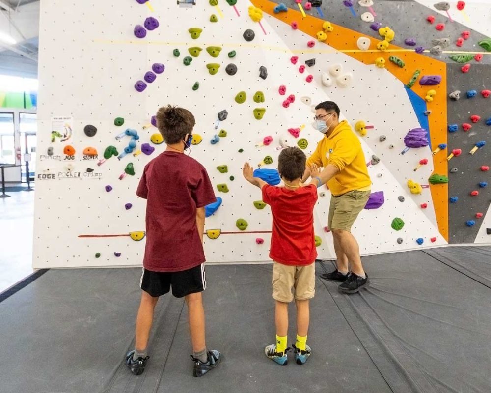 A Hub Climbing Gym employee teaching kids bouldering