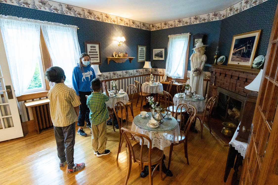 A woman shows a family around the Northern Ontario Railroad Museum tea room