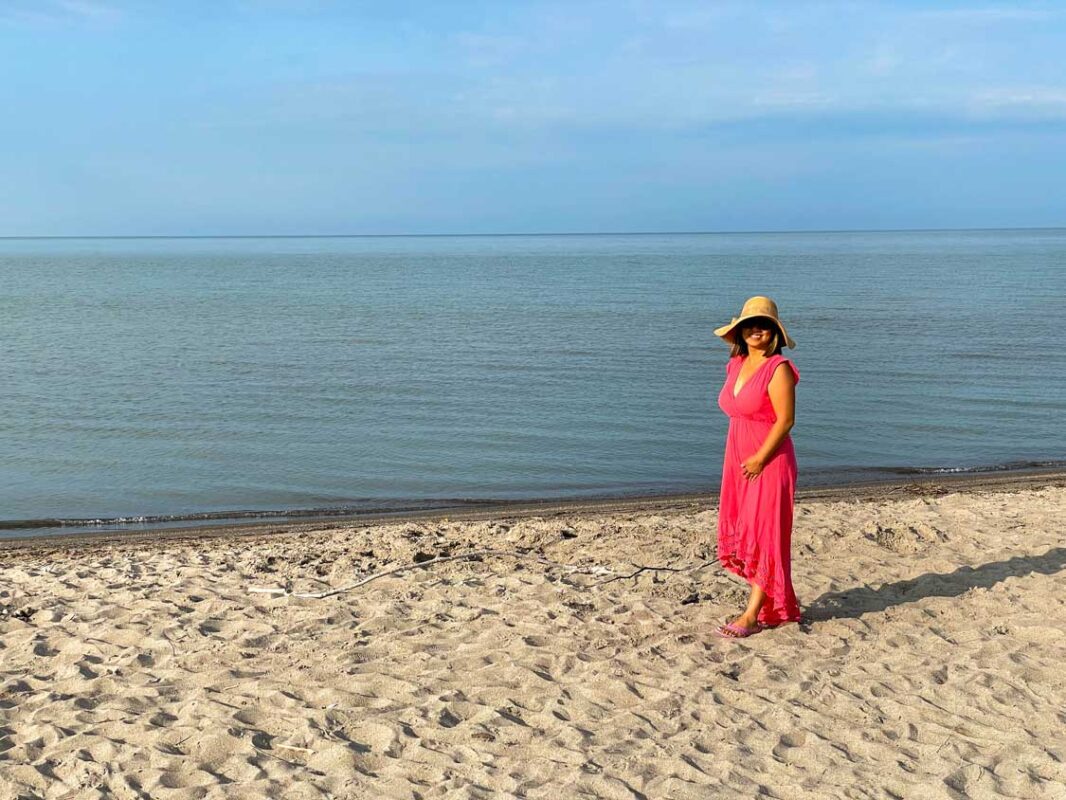 A woman in a red dress walks along Port Burwell Beach in Southwestern Ontario