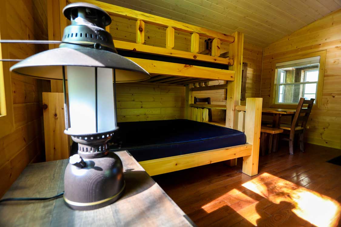 A vintage gas lamp in a wooden cabin with bunk beds