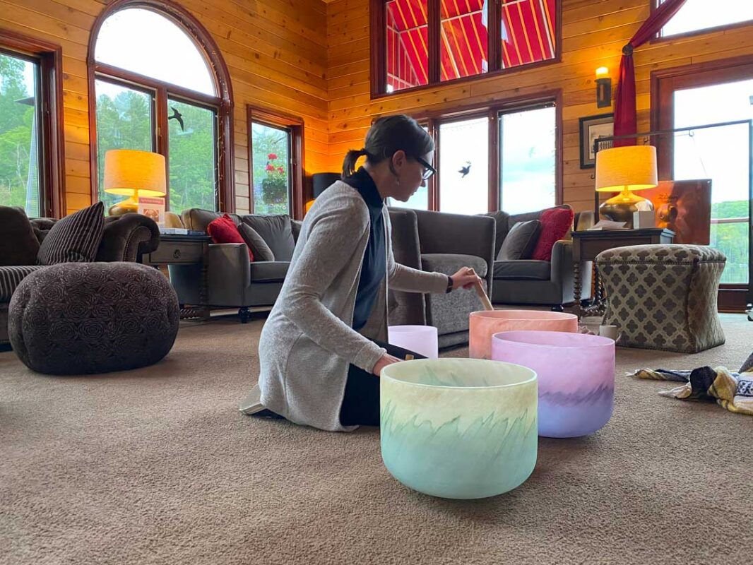 A woman plays music on sound bowls in a large room at Grail Springs Wellness retreat