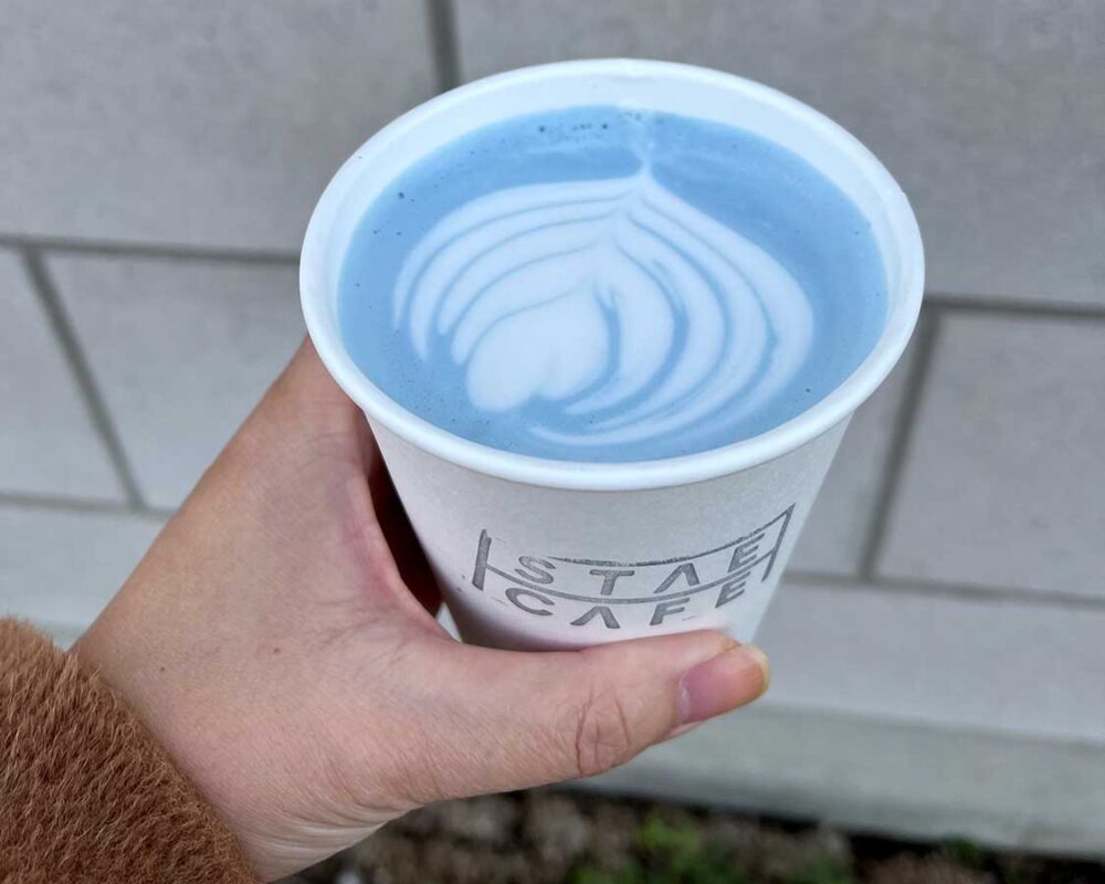 Hand holding lavender coloured coffee from Stae Cafe in Markham
