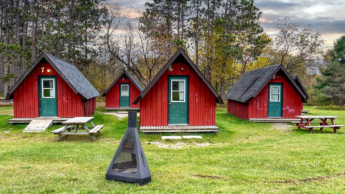 Tiny red cabins with green doors at Mansfield Outdoor Centre in Mulmur, Ontario