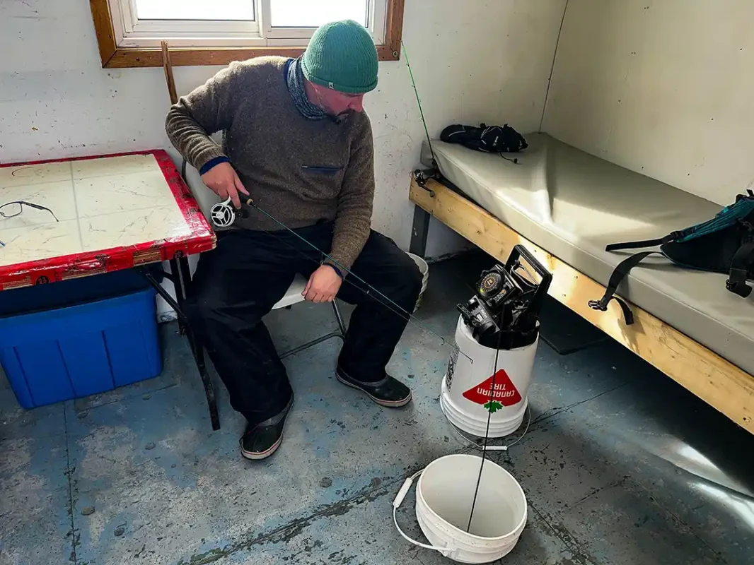 A man looks at a fish finder while ice fishing in North Bay