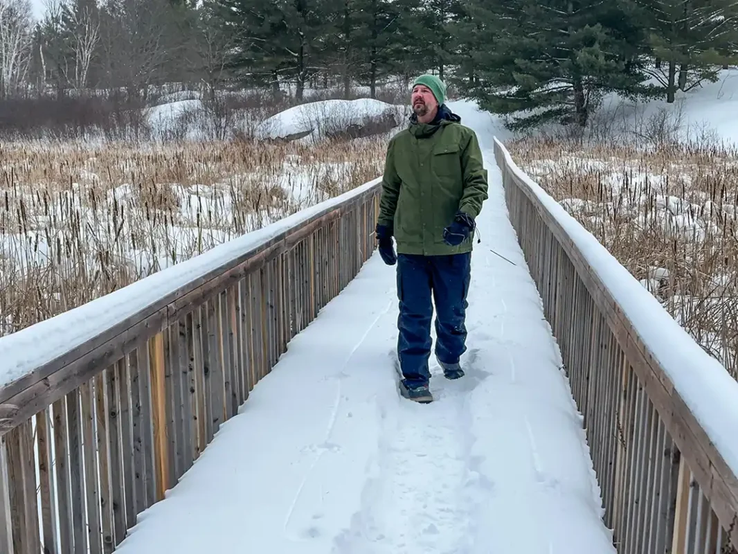 A man winter hiking along a bridge on a section of the Trans Canada Trail near Campbellford Ontario